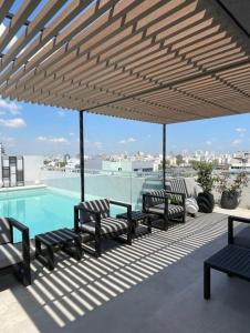 eine Terrasse mit Bänken und ein Swimmingpool mit Markise in der Unterkunft Luxurious and modern Apartment With Cochera Palermo Hollywood in Buenos Aires