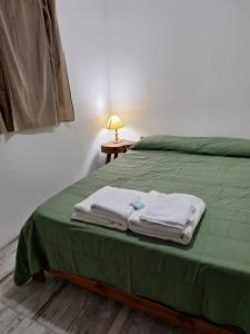 a bedroom with a green bed with towels on it at Alma Campestre in Brandsen +20 photos