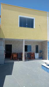 a yellow building with a patio with tables and chairs at Casa de praia Jacuipe Condomínio Planeta Água 2 in Jacuípe