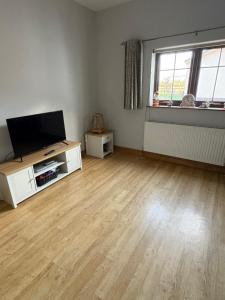 an empty living room with a flat screen tv at Garden cottage in South Collingham