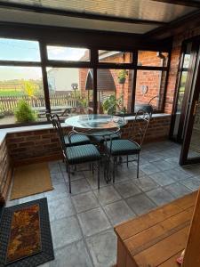 a patio with a glass table and chairs and windows at Garden cottage in South Collingham