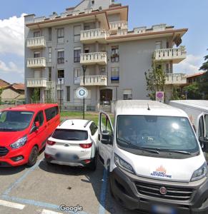 Dos coches estacionados en un estacionamiento frente a un edificio. en La Mansarda, en Melzo