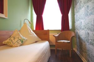 um quarto com uma cama, uma cadeira e uma janela em GastHaus Hotel Bremen em Bremen
