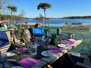 a wooden table with plates and glasses and a view of a lake at North Lakeside B&B Plateliai in Plateliai
