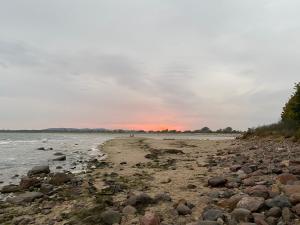 a beach with rocks and a sunset in the background at Auf Feiningers Spuren durch das Mönchgut Doppelzimmer ohne Küche in Lobbe