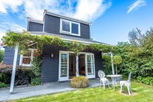 a house with two chairs and a table in the yard at Black Cottage - Beautiful Central Cottage for Two in Rotorua