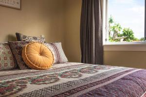 a bed with a pillow on it with a window at Black Cottage - Beautiful Central Cottage for Two in Rotorua