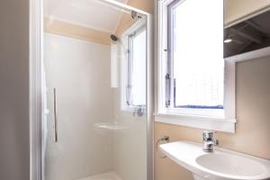 a white bathroom with a sink and a window at Black Cottage - Beautiful Central Cottage for Two in Rotorua +11 photos