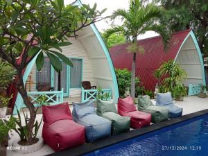 un gruppo di sedie colorate sedute accanto alla piscina di Coral Beach 2 Bungalow a Gili Trawangan