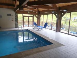 a swimming pool in a house with blue chairs at Studio chaleureux de montagne in Ustou