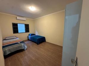 a small room with two beds and a window at Casa Aeroporto Premium Conforto e Conveniência para Sua Estadia in Campo Grande