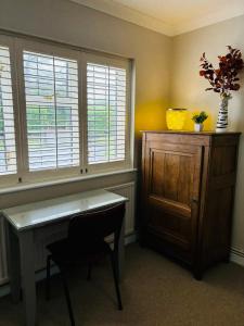 a room with a desk and a cabinet and windows at Little Teagues in East Grinstead
