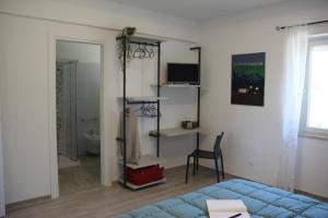 a room with a bed and a desk and a television at Alchemilla Bed & Breakfast in Offida