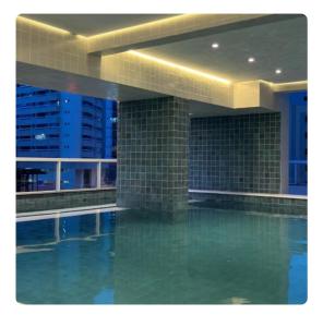 a swimming pool in a building at night at Linda Cobertura vista mar no Residencial Affinity in Praia Grande