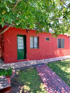a red building with a green door and a tree at Hosteria Alcala in La Falda +11 photos