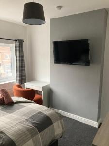 a bedroom with a bed and a flat screen tv on the wall at White Sands, NEWLY renovated central 2 bed house near Cleethorpes beach and all amenities in Cleethorpes