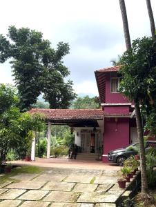 Vintage Coffee Estate 3 Bedrooms 1 Cottage في واياناد: منزل وردي مع سيارة متوقفة في الممر +14 صورة