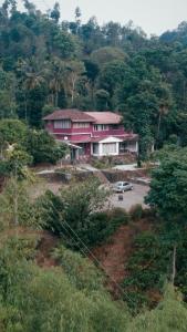 Vintage Coffee Estate 3 Bedrooms 1 Cottage في واياناد: منزل وردي مع سيارة في موقف للسيارات