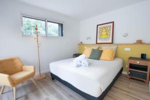 een slaapkamer met een wit bed en een stoel bij La Villa Nature Canopée du Lac in Seignosse +18 foto's