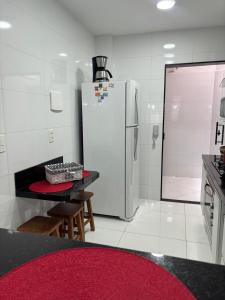 a white kitchen with a refrigerator and a table and chairs at Apartamento a 100 metros da Praia do Forte - Algodoal 206 in Cabo Frio +15 photos
