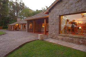 a large stone house with a large window at Los Nobles Hostal de Bosque in Mar del Plata