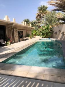 a swimming pool in a villa with a house at Bostan Al-Mostadhill Chalet in Nizwa