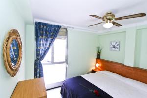Un dormitorio con una cama y un ventilador de techo. en Dms Planetcostadorada, en La Pineda