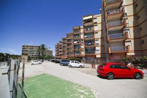 Un coche rojo aparcado delante de un edificio en Dms Planetcostadorada, en La Pineda
