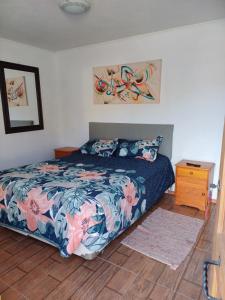 a bedroom with a bed with a floral bedspread at mini apartamento in Coquimbo