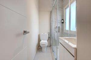 a white bathroom with a toilet and a sink at Hostal Puerta Almar in Estepona