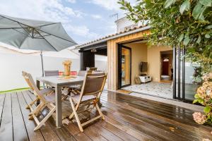 a wooden deck with a table and an umbrella at Villa Marilou à Saint-Martin-De-Ré in Saint-Martin-de-Ré