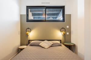 a bedroom with a bed with two lamps and a window at Villa Marilou à Saint-Martin-De-Ré in Saint-Martin-de-Ré