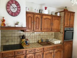 a kitchen with wooden cabinets and a clock on the wall at Villa 2 chambres piscine municipale à 500 m in Arles-sur-Tech