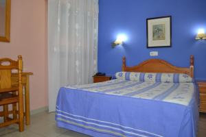 a bedroom with a bed with a blue wall at Hostal Al-Qazeres in Cáceres