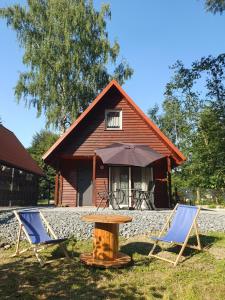 two chairs and a table in front of a house at Opawski Zakątek 43 in Pokrzywna