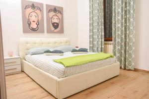 een wit bed in een witte slaapkamer met schilderijen aan de muur bij Anna’s Home in Pompei