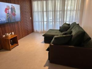 a living room with a green couch and a television at Luxo - Diamantino Residence - 07 in Mucugê