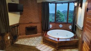 a large bathroom with a tub and a window at Chalés de Analuz in Visconde De Maua