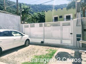 une voiture blanche garée devant une clôture dans l'établissement Casa na praia para até 10 pessoas, à São Sebastião