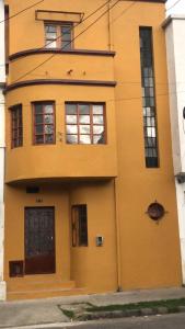 un bâtiment jaune avec des fenêtres et une porte dans l'établissement Helen House, à Bogotá