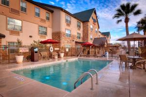 a pool in front of a hotel with tables and umbrellas at TownePlace Suites by Marriott Sierra Vista in Sierra Vista