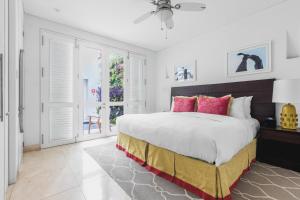 a white bedroom with a large bed with pink pillows at Casa La Cartujita in Cartagena de Indias