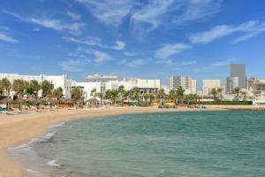 ドーハにあるSharq Village & Spa, a Ritz-Carlton Hotelの長椅子とホテルのあるビーチ