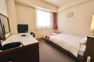 una habitación de hotel con una cama y un escritorio en Hotel Astir Nagoya Sakae, en Aoichō