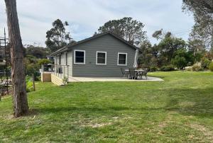 a small house with a picnic table in a yard at Nunyara - BYO Linen in Aireys Inlet