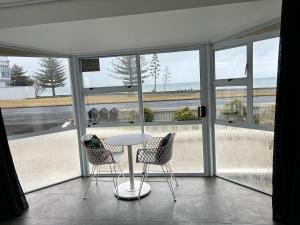 a table and two chairs in a room with windows at Shell's Beachfront BnB in Napier