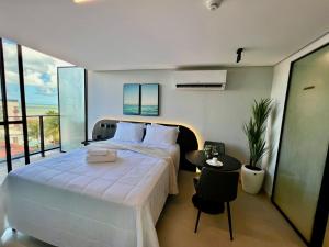 a bedroom with a large white bed and a table at Alta Garden- Pé Na Areia- MH in João Pessoa