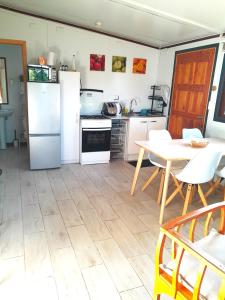 een keuken met witte apparatuur en een tafel en stoelen bij Cabaña Familiar Puerto Varas in Puerto Varas