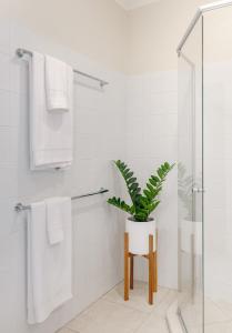 a bathroom with a plant sitting on a stool at The Sunshine Beach Luxe Coastal Retreat in Sunshine Beach +31 photos