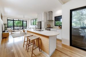 a kitchen with white cabinets and a large island with stools at The Sunshine Beach Luxe Coastal Retreat in Sunshine Beach